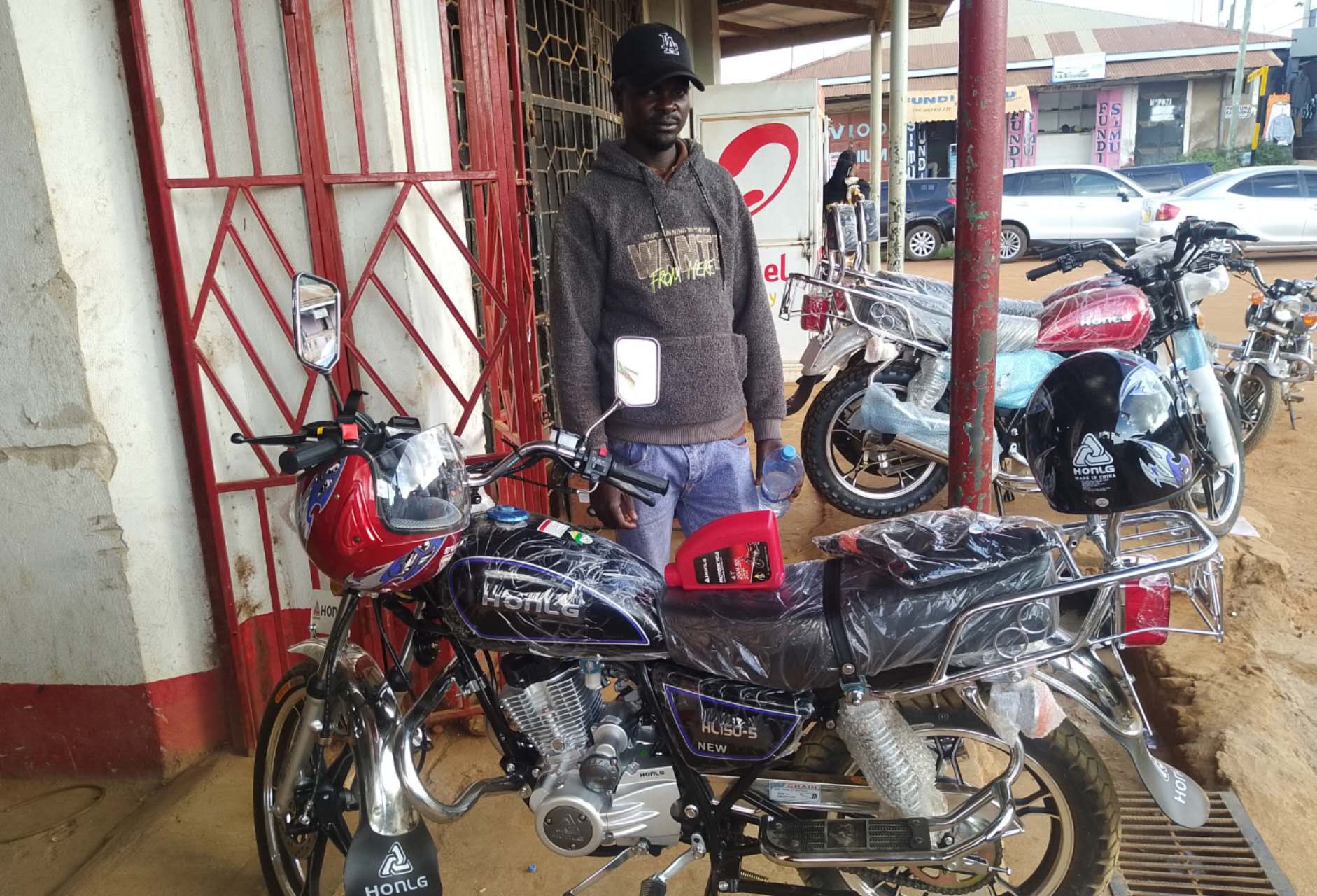 HONLG Tanzania customer standing with a newly delivered black motorcycle
