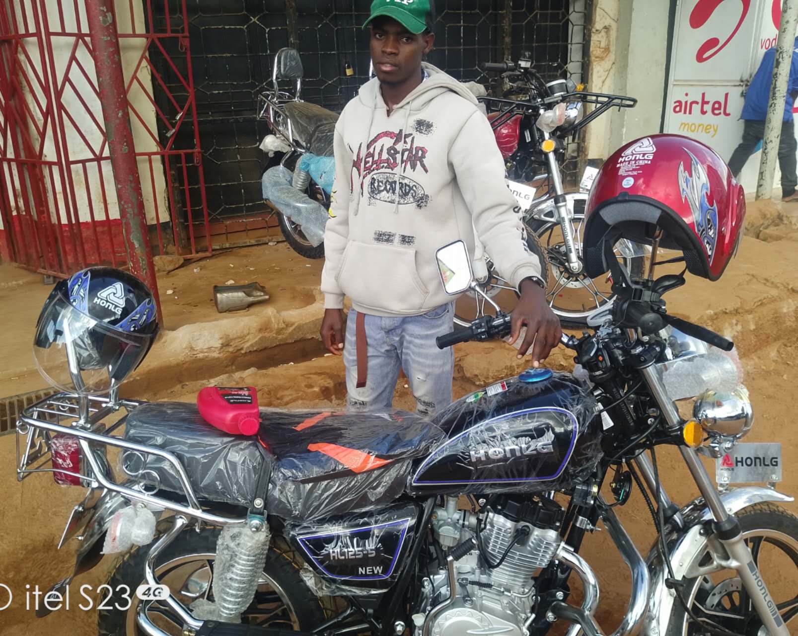 HONLG Tanzania rider with a black motorcycle outside a local shop