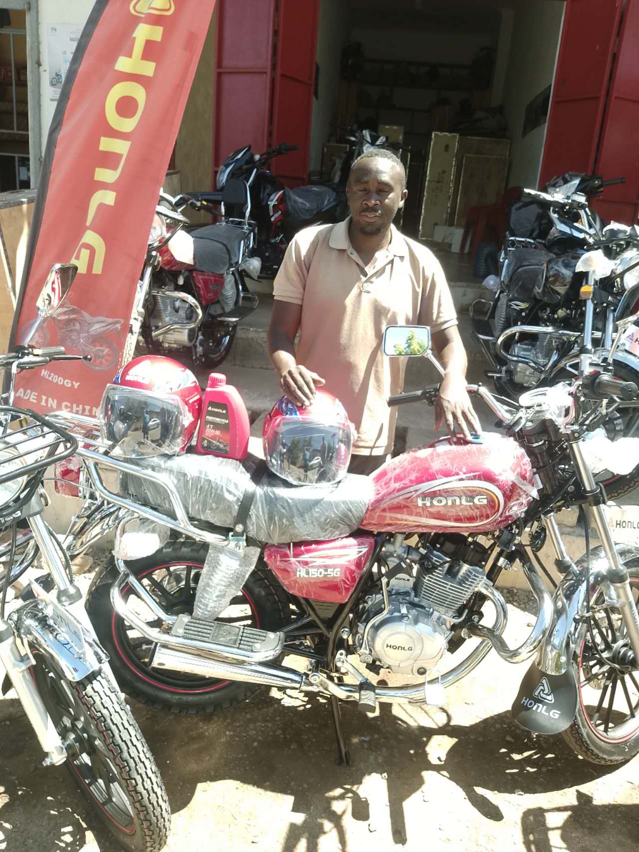 HONLG Tanzania customer with a red motorcycle outside a local dealer shop